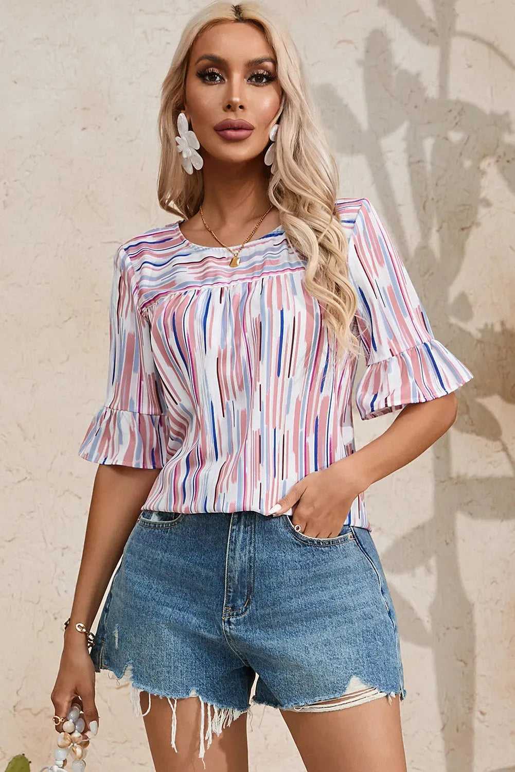 Rainbow Stripe Splash Blouse paired with distressed denim shorts, showcasing its colorful print and relaxed fit for summer fashion.