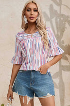 Rainbow Stripe Splash Blouse paired with distressed denim shorts, showcasing its colorful print and relaxed fit for summer fashion.