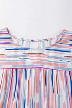 Close-up of the blouse neckline showing the detailed brushstroke pattern and soft fabric texture of the Rainbow Stripe Splash Blouse.