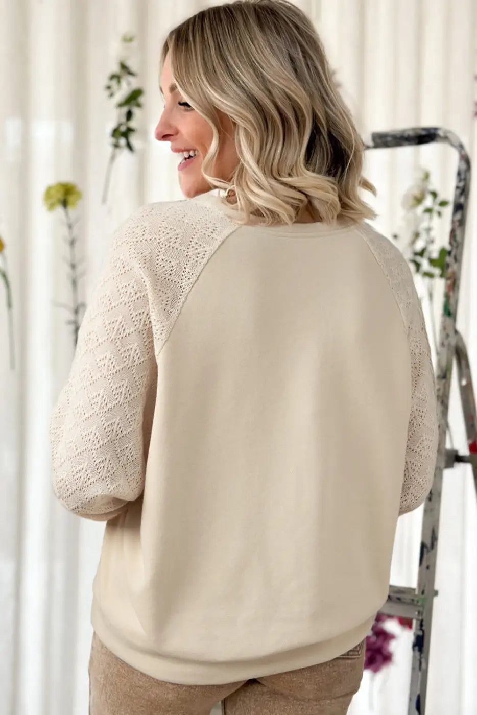 Blonde woman smiling in a vintage patchwork eyelet jumper, cream-colored knit sweater