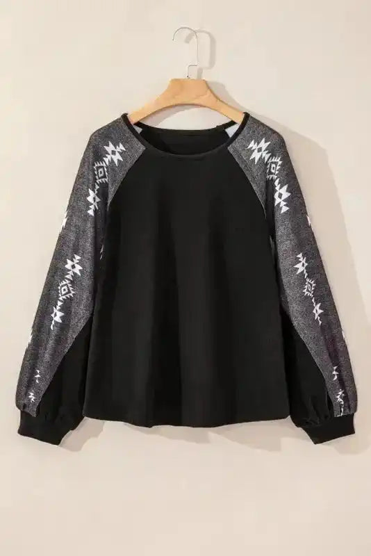 Flat lay of black Western Print Patch Long Sleeve Top with grey Aztec sleeves, highlighting its fleece texture and casual design.
