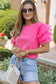 Woman in bright pink whimsical wave blouse with ruffled sleeves and sunglasses