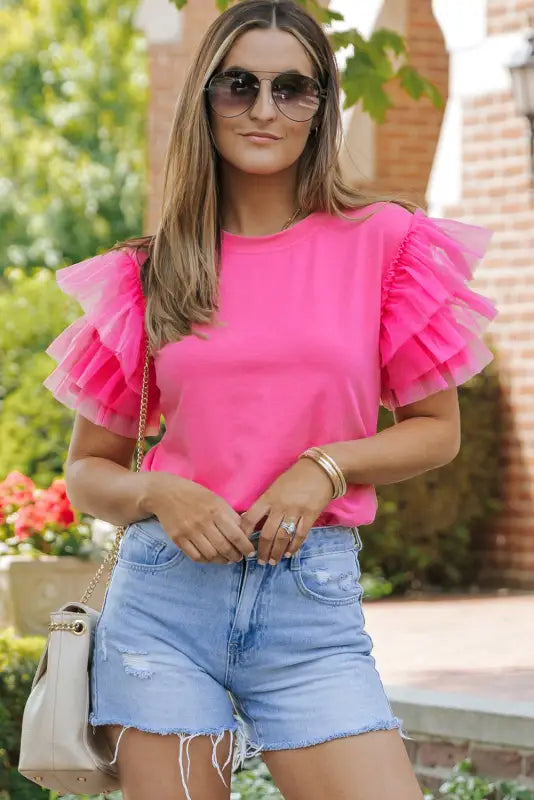 Woman in denim shorts wearing a whimsical wave blouse with ruffled sleeves