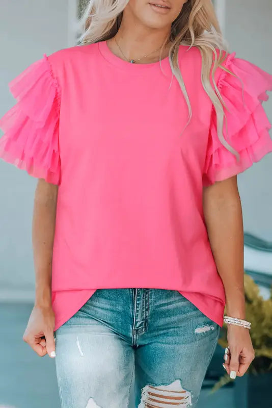 Woman in whimsical wave blouse, bright pink t-shirt with blue jeans, colorful backdrop