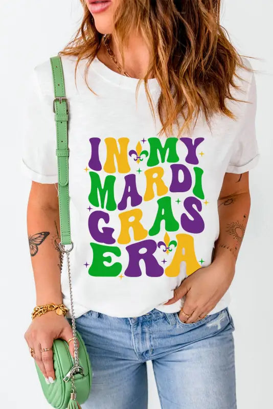 White crew neck t-shirt with colorful ’in my mardi gras era’ design, ideal for relaxed style