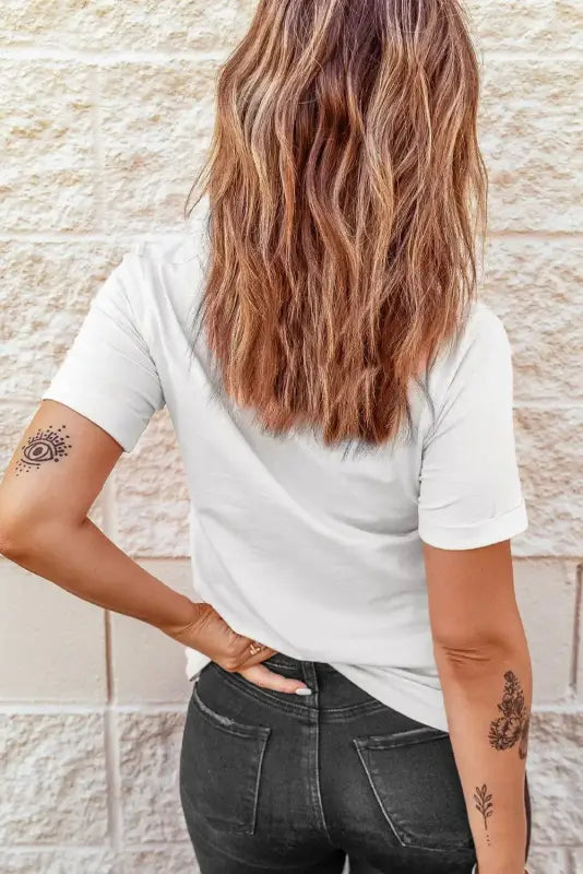 Woman with long wavy brown hair wearing a white crew neck t-shirt and dark jeans, relax relax