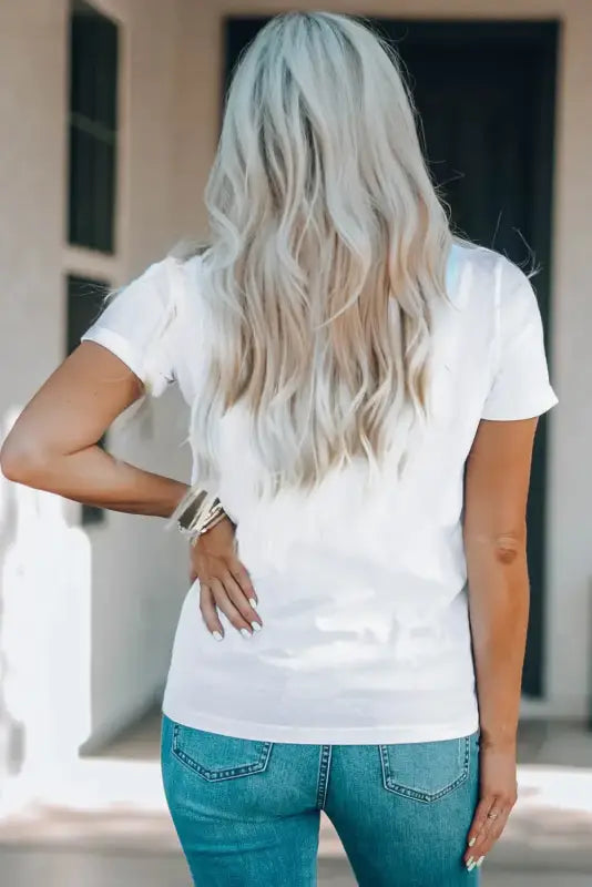 Long, wavy platinum blonde hair with crew neck white t-shirt; blue jeans for a relax relax look