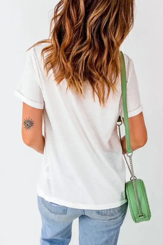 Woman in white casual plain crew neck t-shirt and jeans with a green handbag