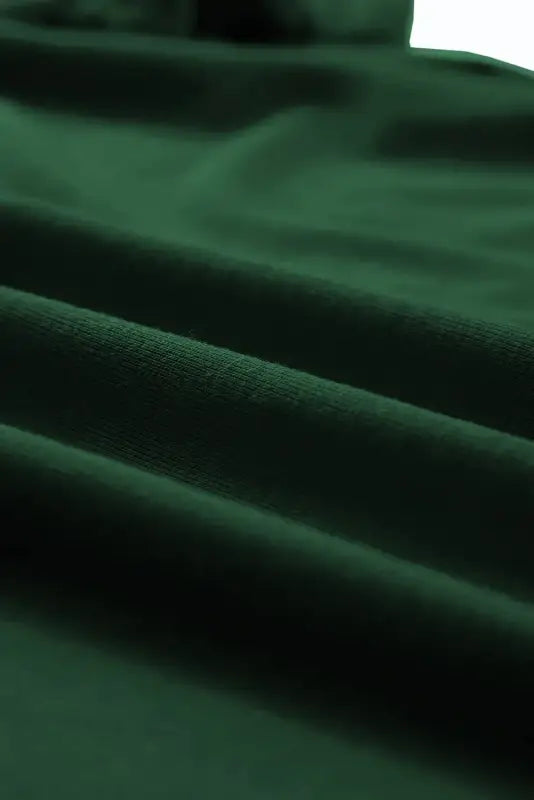 Soft, undulating folds of deep green velvet fabric on white casual plain crew neck t-shirt