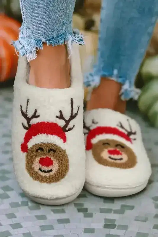 White Christmas deer slippers with red Santa hat and antlers, perfect for cozy indoor winter wear. Plush fleece design for festive comfort.
