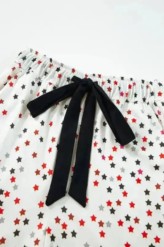 Close-up of pyjama pants waistband from White Star Panel Pyjama Set with black bow tie and red-black star print. Elastic waist for comfort.
