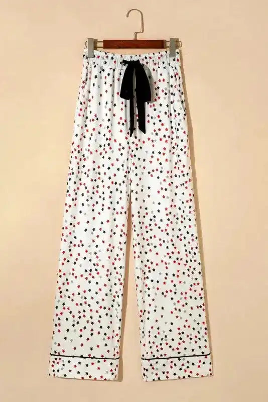 White Star Panel Pyjama Set pants displayed on hanger with black ribbon tie and star pattern. Stylish and soft women’s sleepwear trousers.