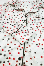 Detail of White Star Panel Pyjama Set top showing black piping, buttons, and star print. Classic collar design for elegant loungewear.