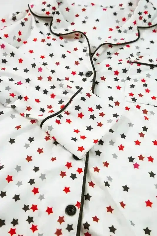 Detail of White Star Panel Pyjama Set top showing black piping, buttons, and star print. Classic collar design for elegant loungewear.