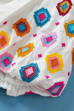 Close-up of embroidered floral pattern on white cotton fabric