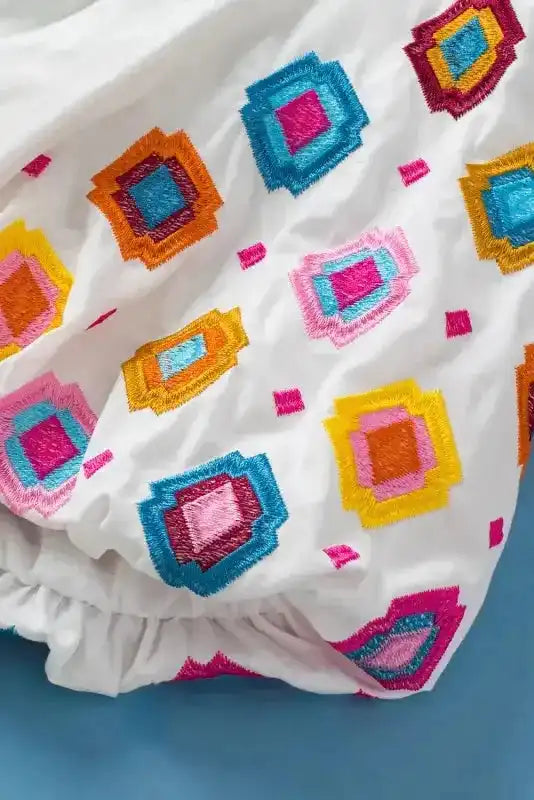 Close-up of embroidered floral pattern on white cotton fabric