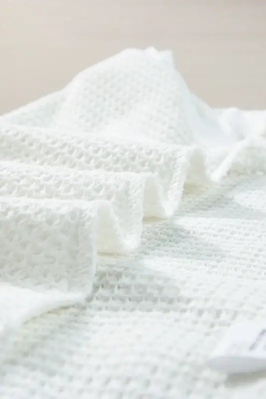 White textured paper towels or tissues folded, stacked in front of a white flowy tunic tank top