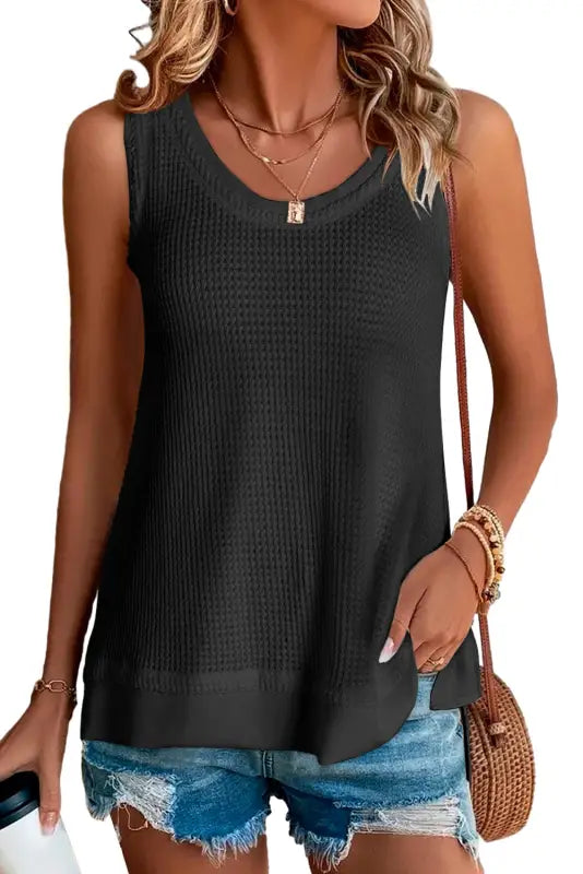 Black sleeveless knit top with scoop neckline, perfect for layering under a white flowy tunic