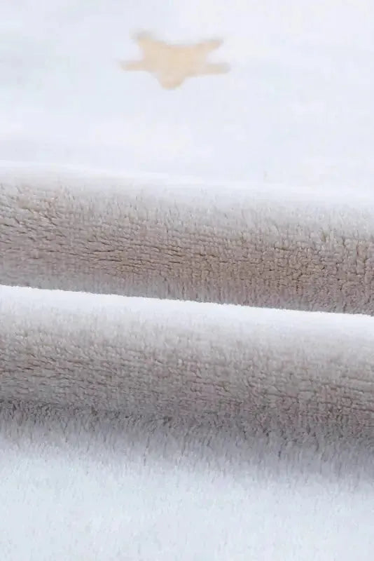 Close-up of soft fabric showing white plush lounge set with a cozy texture and star detail
