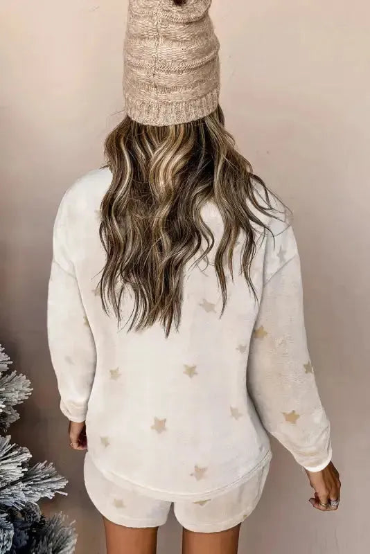 Back view of a woman in a white plush lounge set with star patterns, styled with a cozy hat