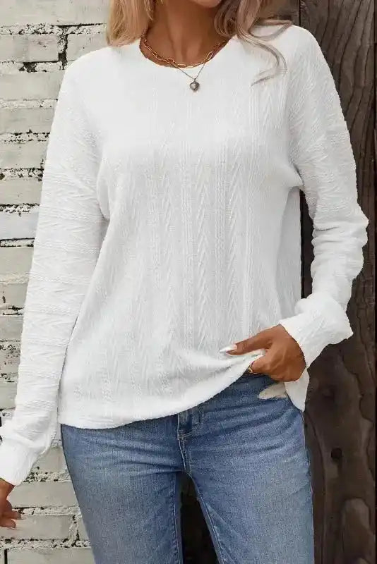 White Round Neck Drop Shoulder Textured Knit Top - Long paired with jeans, highlighting its cozy ribbed texture and casual silhouette.