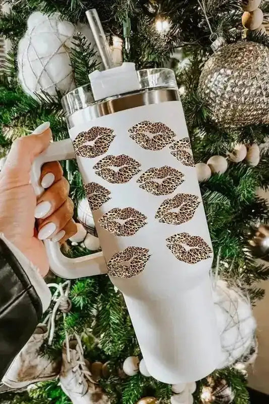 White Leopard Lips Thermos Cup with 1200ml capacity, featuring Valentine print and built-in straw, held in front of a decorated Christmas tree.